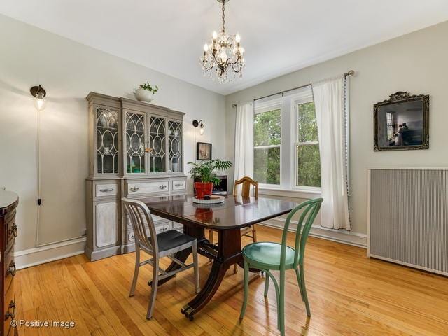 dining space featuring radiator, light wood-type flooring, and a notable chandelier