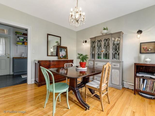 dining area with light wood-type flooring, an inviting chandelier, and radiator heating unit