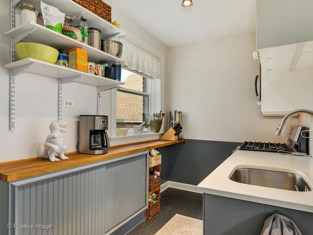 kitchen featuring baseboards, light countertops, gray cabinetry, open shelves, and a sink