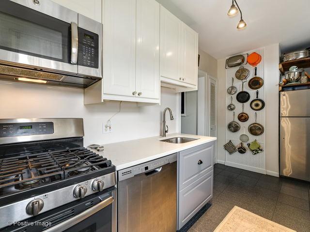 kitchen with baseboards, white cabinets, stainless steel appliances, light countertops, and a sink