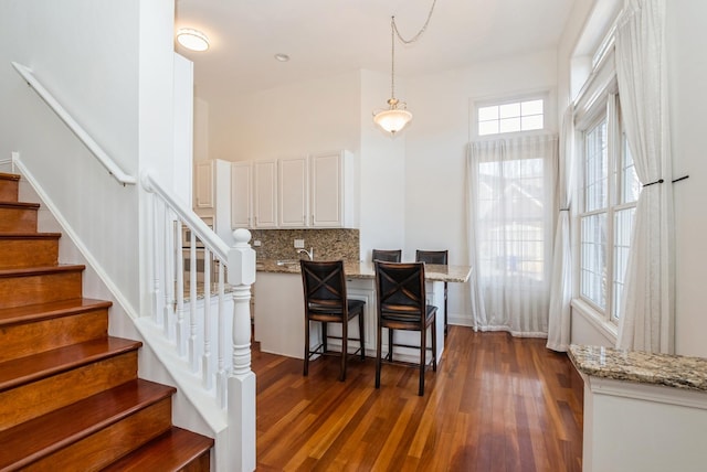 dining space featuring stairway and dark wood-style flooring