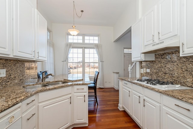 kitchen with white appliances, dark wood-style floors, a sink, under cabinet range hood, and white cabinetry