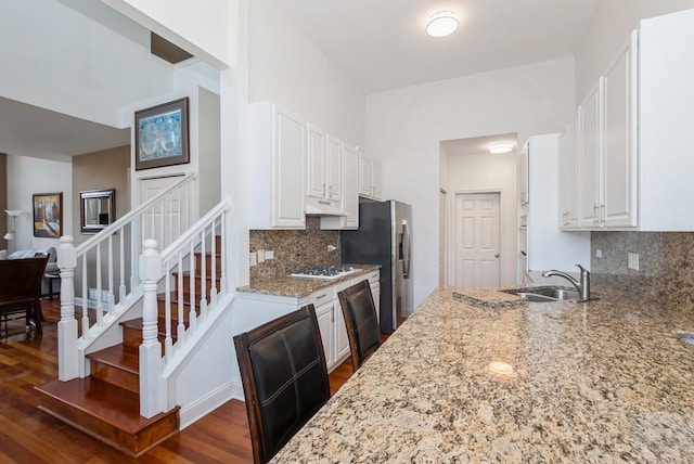 kitchen featuring light stone countertops, a sink, dark wood-type flooring, white cabinets, and stainless steel fridge