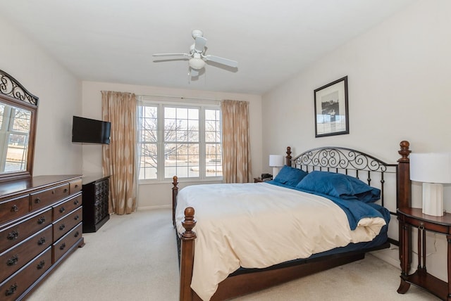 bedroom with multiple windows, a ceiling fan, baseboards, and light carpet