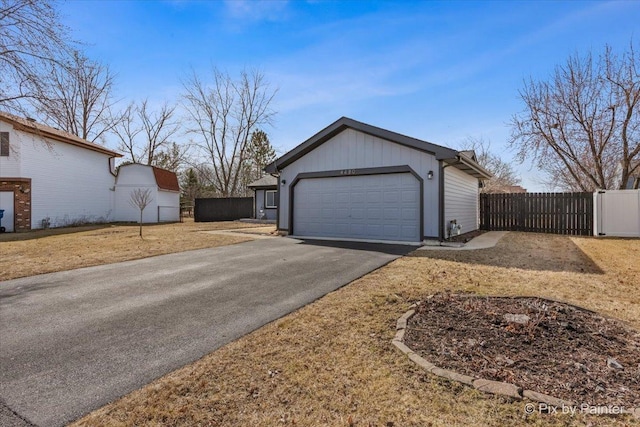 garage featuring driveway and fence