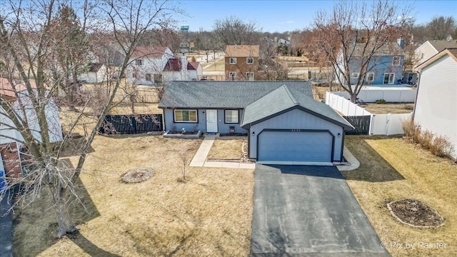 ranch-style home featuring driveway, an attached garage, a front lawn, fence private yard, and a residential view