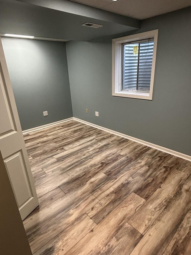 basement with baseboards, visible vents, and wood finished floors