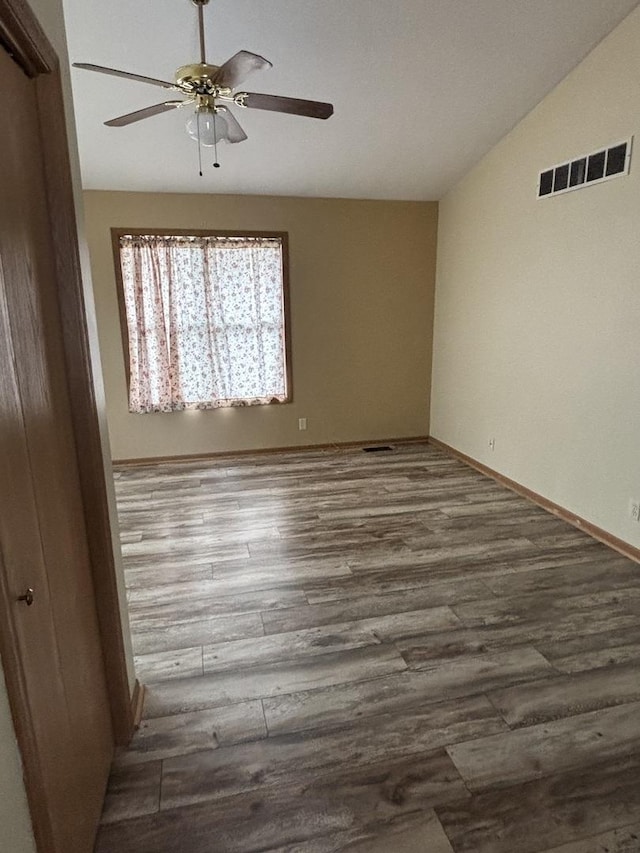 spare room featuring lofted ceiling, visible vents, ceiling fan, and wood finished floors