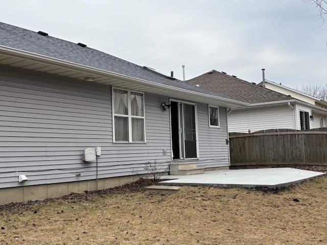 rear view of property with a shingled roof, entry steps, a patio area, and fence