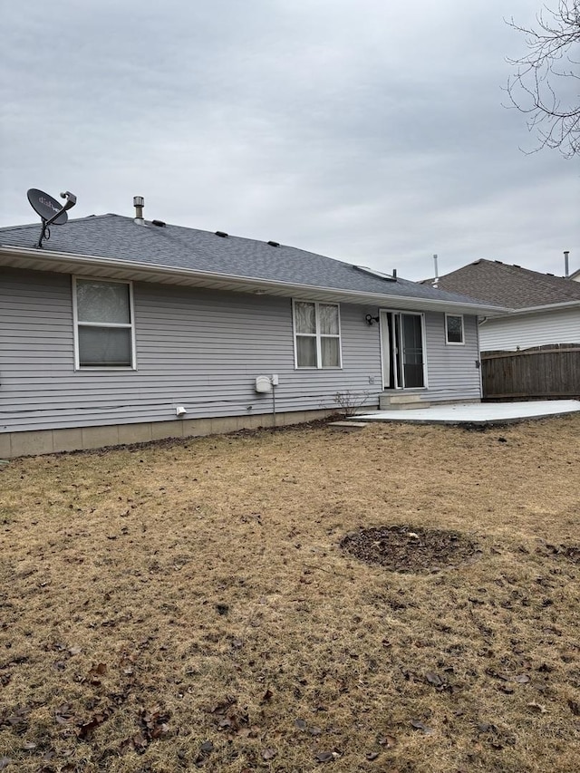 rear view of property with a patio, a shingled roof, and fence