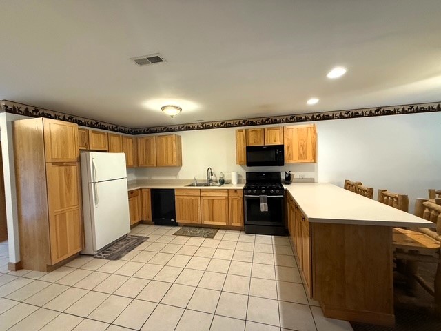 2643 N Il Route 178th Hwy Unit 2-2, Utica, IL 61373 - kitchen with black appliances, a peninsula, light countertops, a sink, and light tile patterned floors