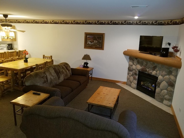 living room featuring baseboards, visible vents, and a stone fireplace