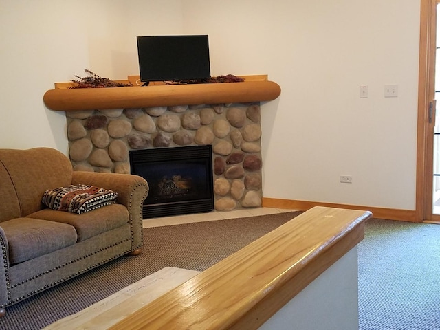 carpeted living area with baseboards and a stone fireplace