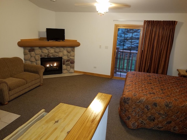 bedroom with baseboards, ceiling fan, access to exterior, carpet flooring, and a stone fireplace