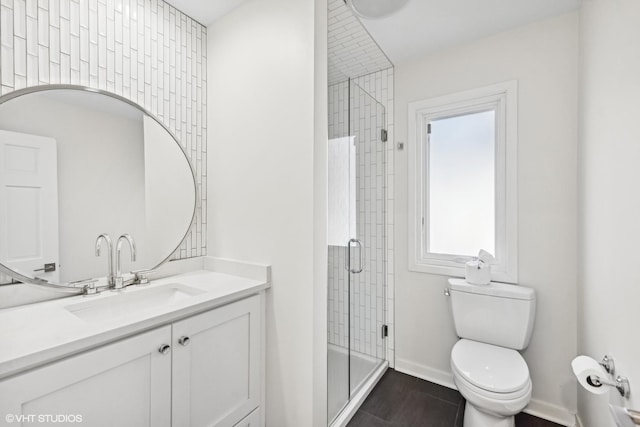 full bath with a stall shower, vanity, toilet, and baseboards