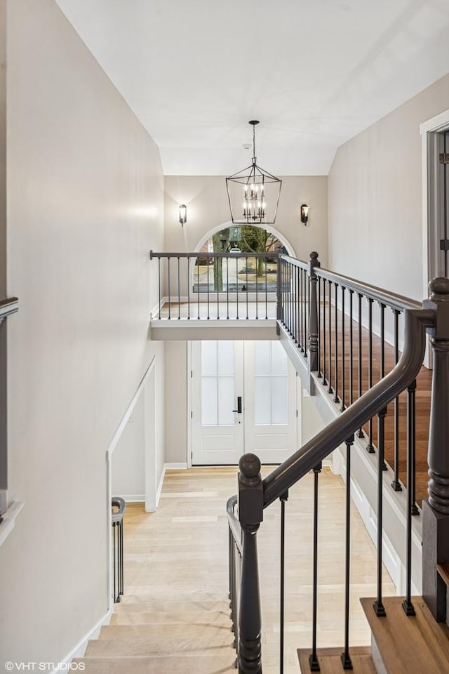 stairway featuring baseboards, a notable chandelier, and wood finished floors