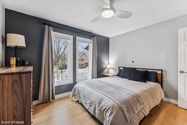 bedroom with a ceiling fan, light wood-style flooring, and baseboards