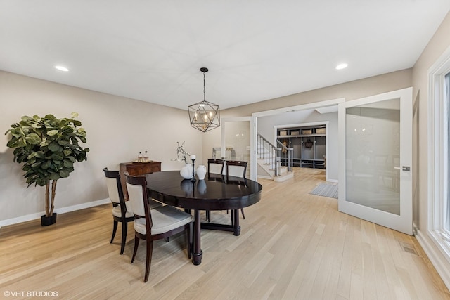 dining space featuring recessed lighting, a notable chandelier, baseboards, stairs, and light wood-type flooring