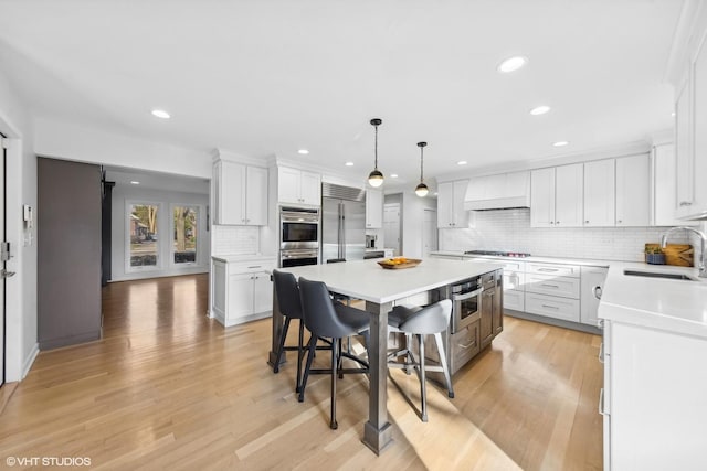 kitchen with light wood finished floors, stainless steel appliances, a sink, and a center island