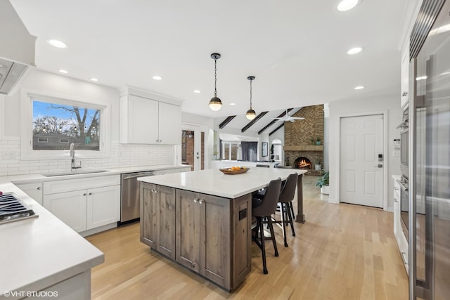 kitchen featuring open floor plan, a center island, a sink, stainless steel appliances, and backsplash