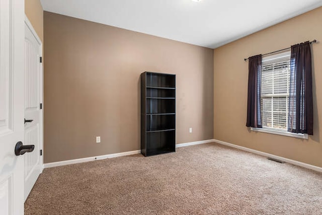 carpeted spare room with visible vents and baseboards