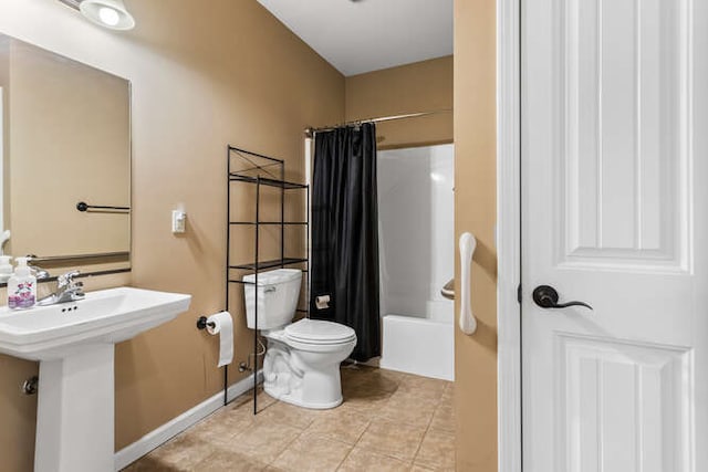 bathroom with baseboards, a sink, tile patterned flooring, toilet, and shower / tub combo with curtain