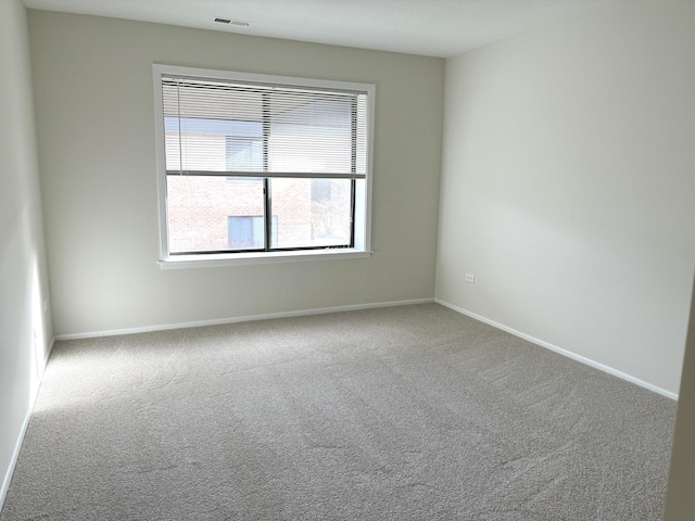 carpeted spare room featuring visible vents and baseboards