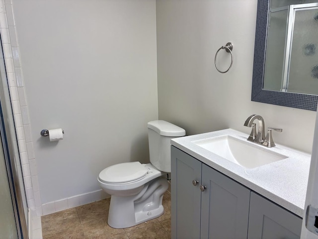 bathroom with toilet, a shower stall, vanity, baseboards, and tile patterned floors