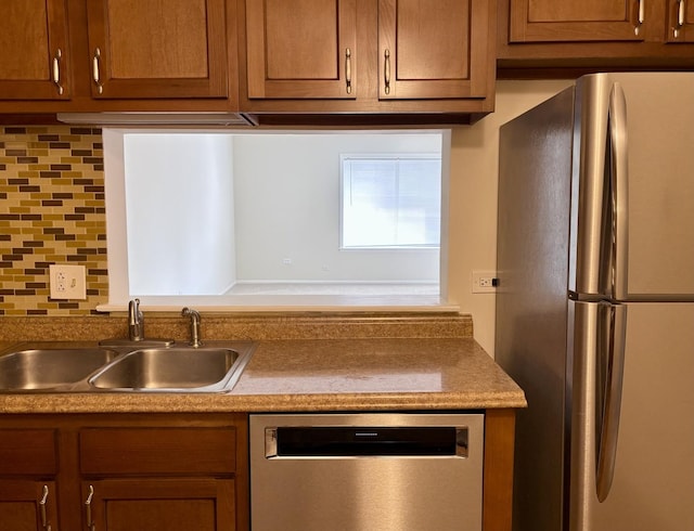 kitchen featuring tasteful backsplash, appliances with stainless steel finishes, brown cabinets, and a sink