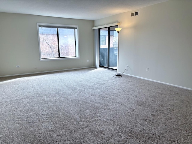 carpeted empty room with visible vents and baseboards