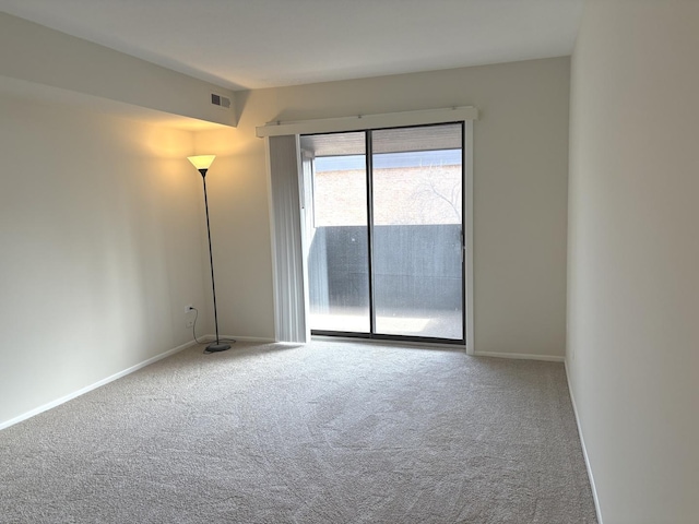 empty room with carpet floors, visible vents, and baseboards