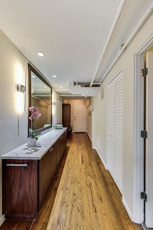 corridor with recessed lighting, wood finished floors, visible vents, and baseboards