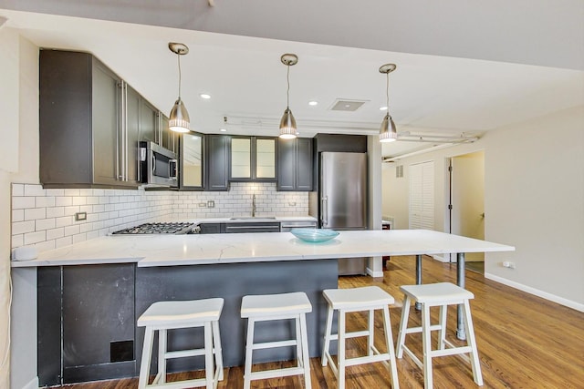 kitchen with backsplash, a breakfast bar area, appliances with stainless steel finishes, a peninsula, and a sink