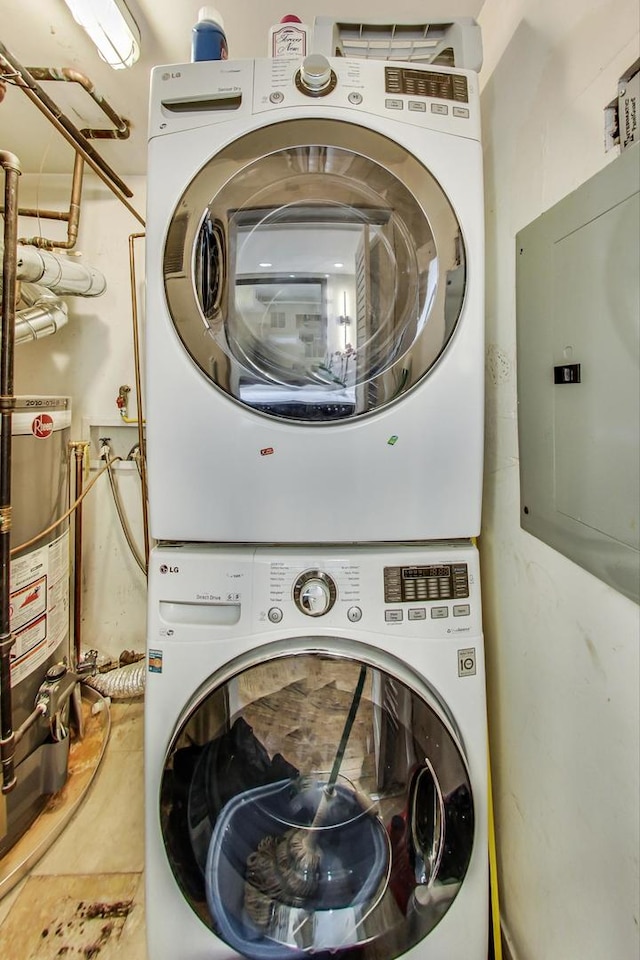 laundry room with electric panel, stacked washer and dryer, laundry area, and water heater