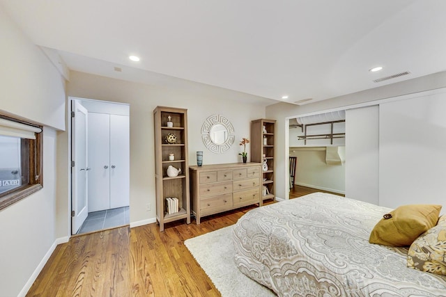 bedroom with wood finished floors, visible vents, baseboards, recessed lighting, and a closet