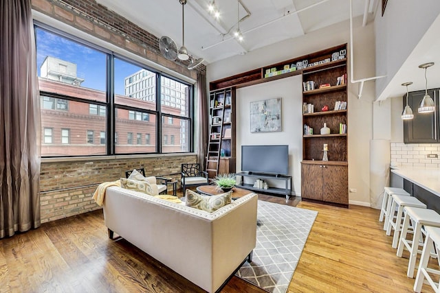 living area with light wood finished floors, baseboards, and brick wall