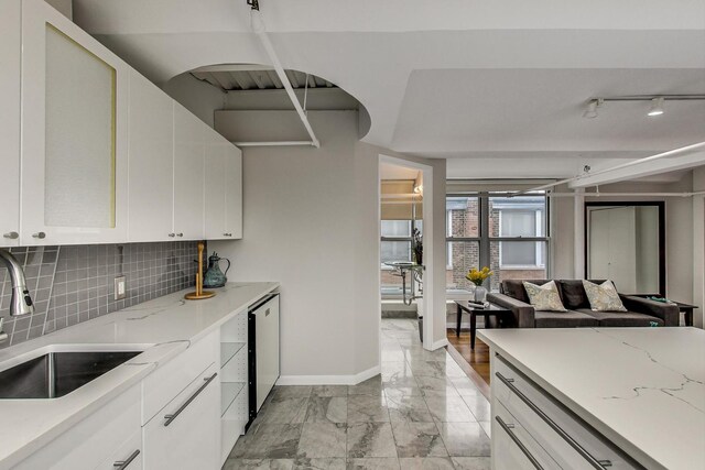 kitchen with baseboards, white dishwasher, a sink, marble finish floor, and backsplash