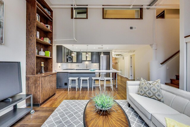 living area with visible vents, dark wood finished floors, and stairs