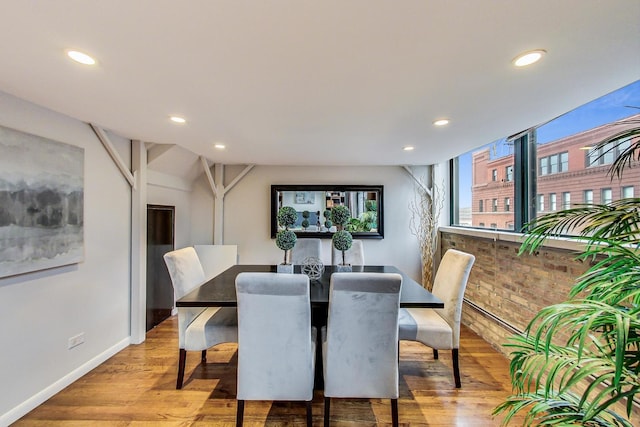 dining area with recessed lighting, light wood-style flooring, brick wall, and baseboards