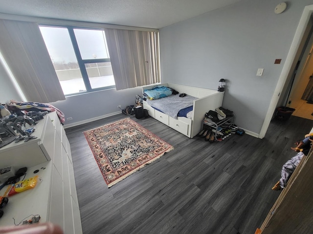 bedroom with a textured ceiling, dark wood finished floors, and baseboards