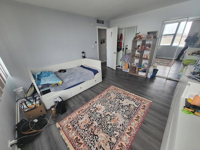 bedroom with a textured ceiling, a closet, wood finished floors, and visible vents