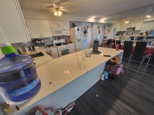 kitchen with white appliances, dark wood-style flooring, a ceiling fan, white cabinetry, and decorative backsplash