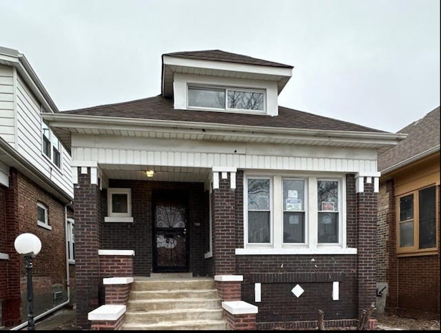 view of front facade with a shingled roof and brick siding