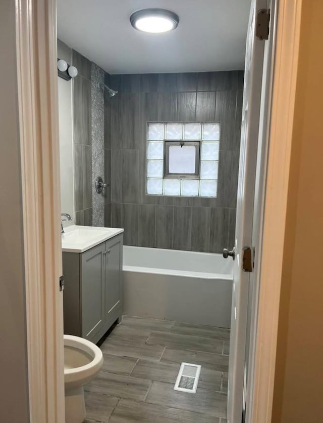 bathroom with shower / washtub combination, wood finish floors, vanity, and visible vents