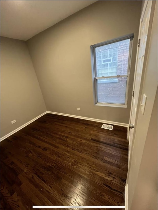 empty room featuring visible vents, dark wood finished floors, and baseboards