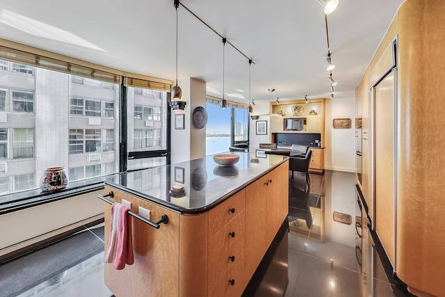 kitchen featuring a center island, pendant lighting, dark countertops, rail lighting, and dark tile patterned floors