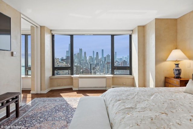 bedroom with a view of city, baseboards, and wood finished floors