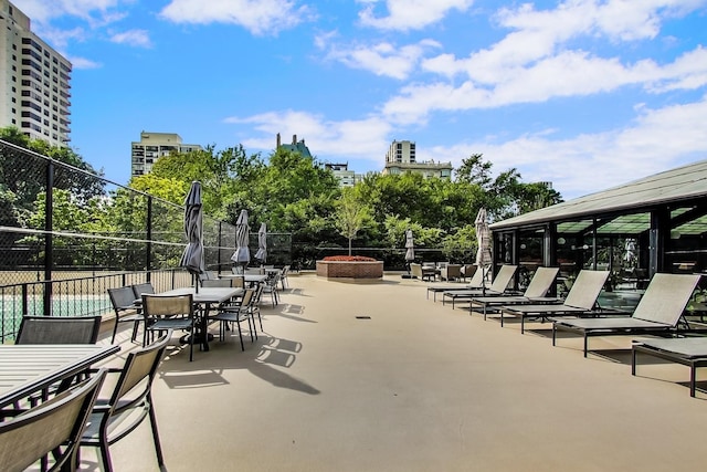 surrounding community featuring outdoor dining area, a fire pit, fence, a view of city, and a patio area