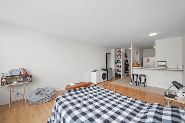 bedroom featuring light wood-type flooring, washing machine and dryer, a closet, and freestanding refrigerator