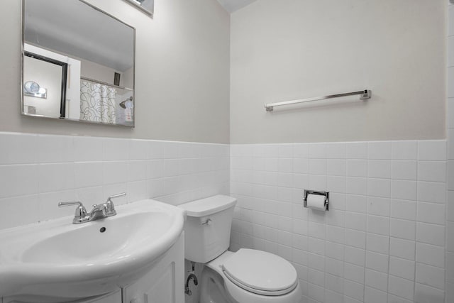 full bathroom with a wainscoted wall, vanity, toilet, and tile walls